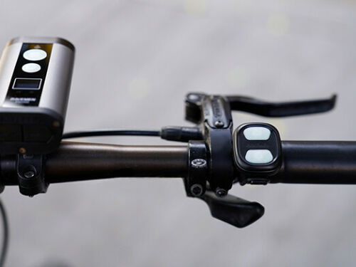 Ravemen Wireless 900/2400 LUMEN USB RECHARGEABLE HEADLIGHT on a bike handlebar along with the wireless controller.